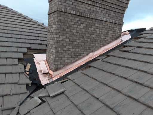 Large copper chimney flashing on slate roof